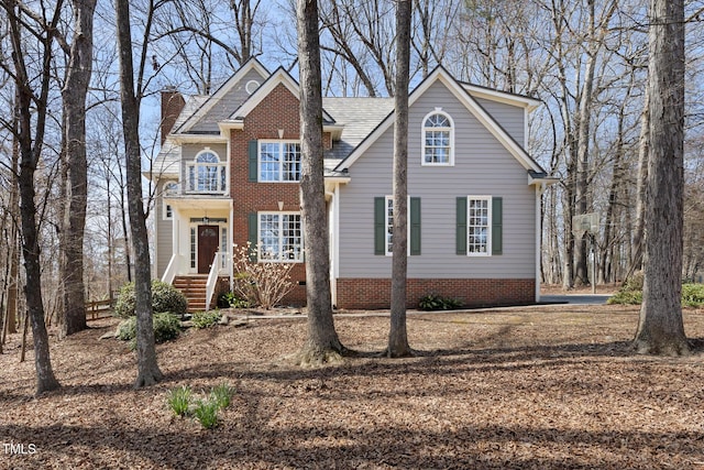 traditional home with brick siding, a balcony, and a chimney