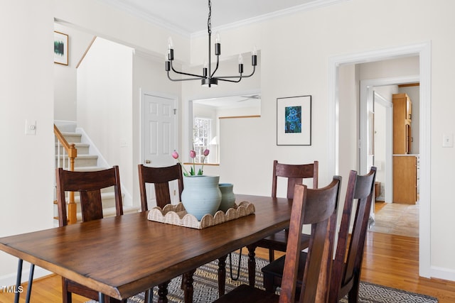 dining room featuring stairway, baseboards, light wood-style flooring, crown molding, and a notable chandelier