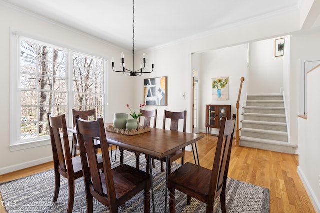 dining space featuring a notable chandelier, light wood-style flooring, stairs, and ornamental molding