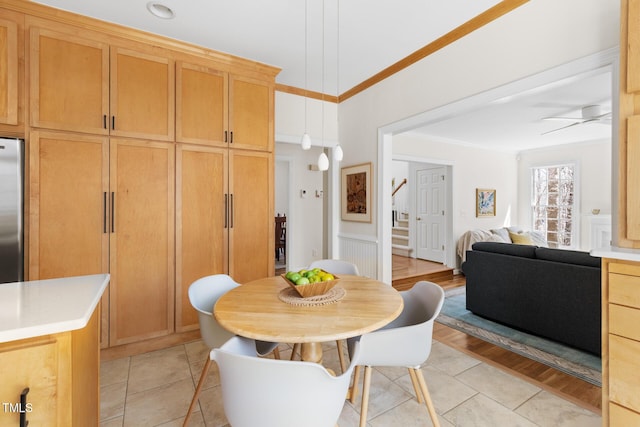 dining space with a ceiling fan, light wood-style flooring, stairs, and crown molding