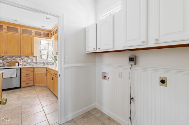 laundry area with wainscoting, hookup for a washing machine, cabinet space, hookup for an electric dryer, and a sink
