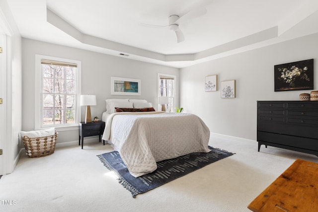 carpeted bedroom featuring visible vents, ceiling fan, baseboards, and a tray ceiling
