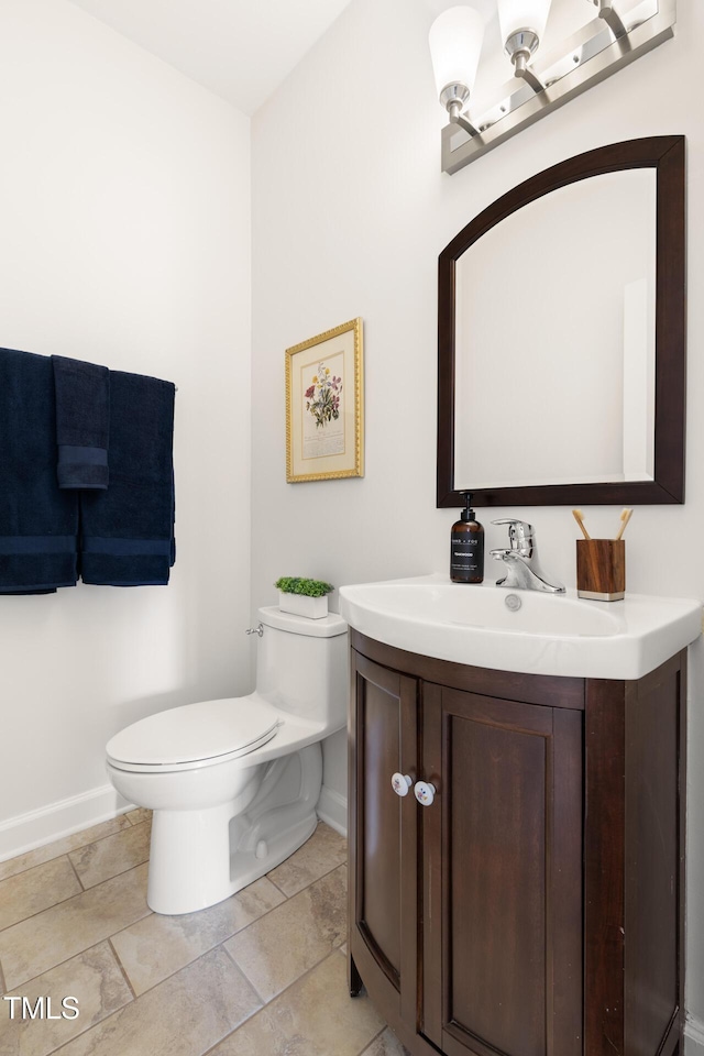 bathroom with baseboards, toilet, and vanity