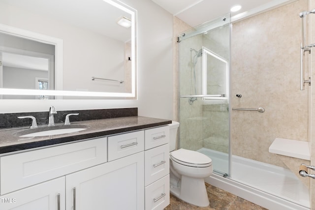full bathroom featuring toilet, a stall shower, and vanity