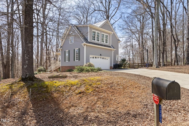 view of front of property featuring an attached garage, concrete driveway, and fence