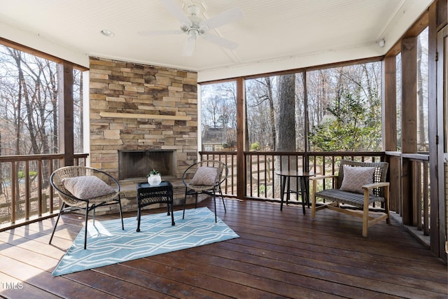 sunroom / solarium featuring an outdoor stone fireplace and a ceiling fan
