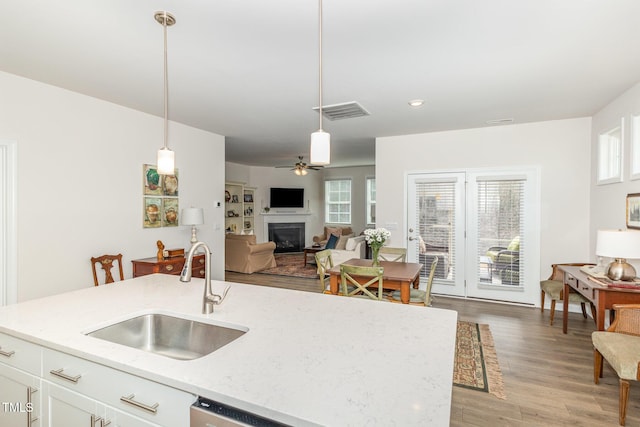 kitchen with visible vents, pendant lighting, a sink, open floor plan, and a fireplace