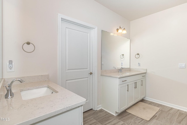 full bathroom with a sink, baseboards, and two vanities