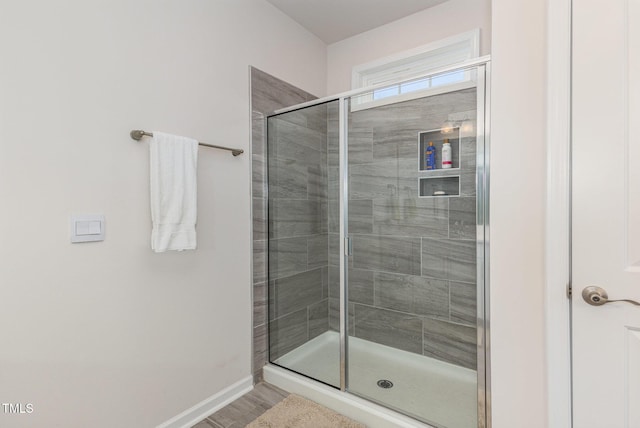 bathroom featuring wood finished floors, baseboards, and a stall shower