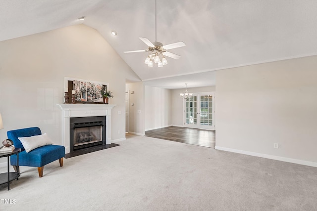 living room featuring baseboards, a fireplace with flush hearth, carpet flooring, ceiling fan with notable chandelier, and high vaulted ceiling