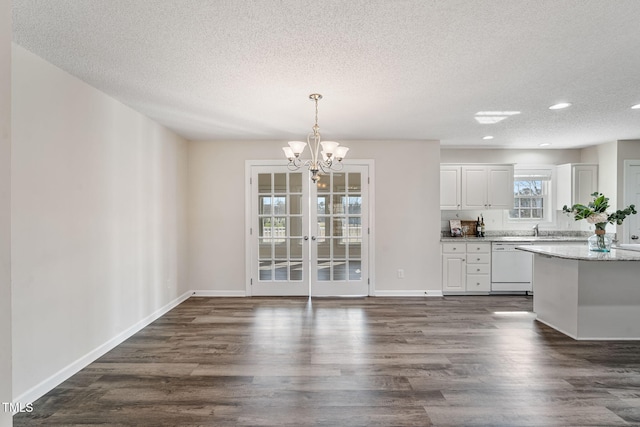 kitchen with a notable chandelier, dark wood-style floors, white cabinets, baseboards, and dishwasher