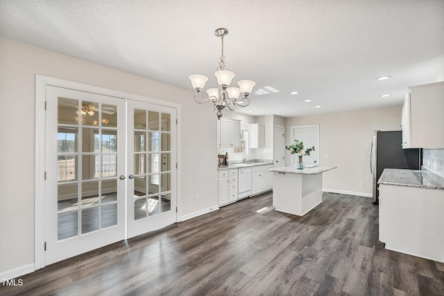 kitchen with a center island, white dishwasher, a notable chandelier, white cabinets, and dark wood-style flooring