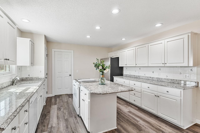 kitchen featuring a sink, white appliances, a kitchen island, and white cabinets