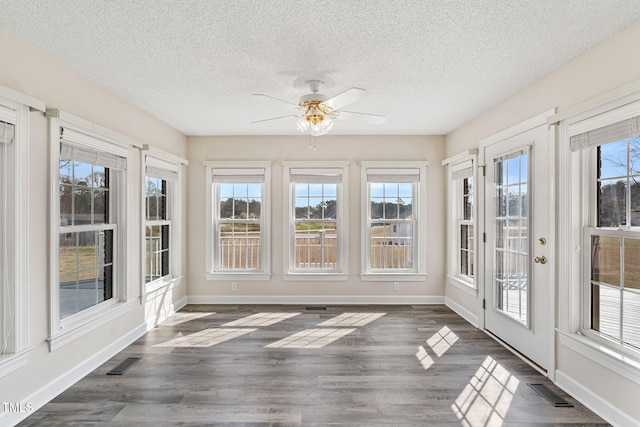 unfurnished sunroom with visible vents, a healthy amount of sunlight, and a ceiling fan