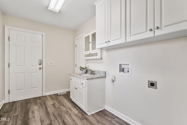 laundry area with hookup for a washing machine, baseboards, hookup for an electric dryer, cabinet space, and dark wood-type flooring