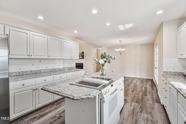 kitchen featuring a center island, light wood finished floors, white appliances, and white cabinetry