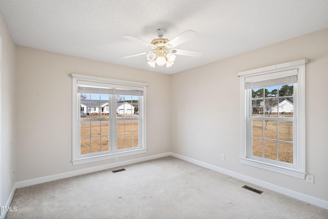 spare room with carpet flooring, a healthy amount of sunlight, and visible vents