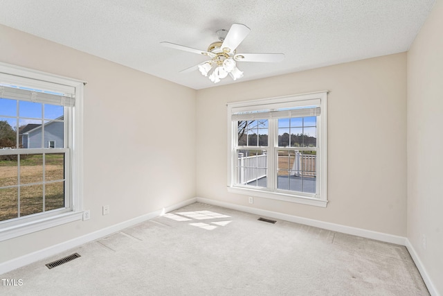 carpeted spare room with visible vents, baseboards, and a textured ceiling