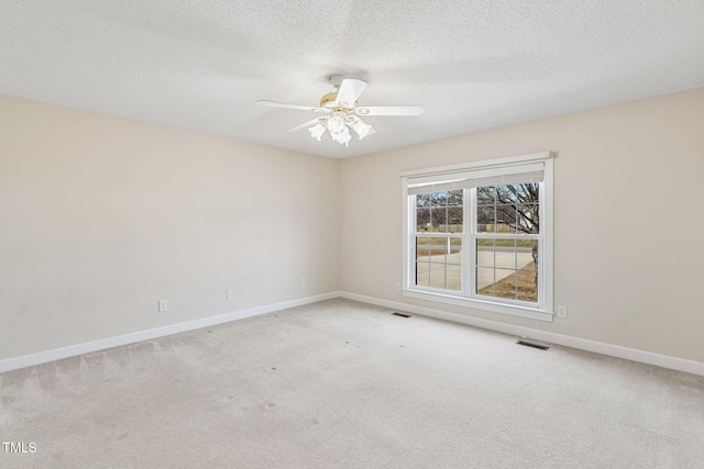 carpeted empty room with a ceiling fan, baseboards, visible vents, and a textured ceiling