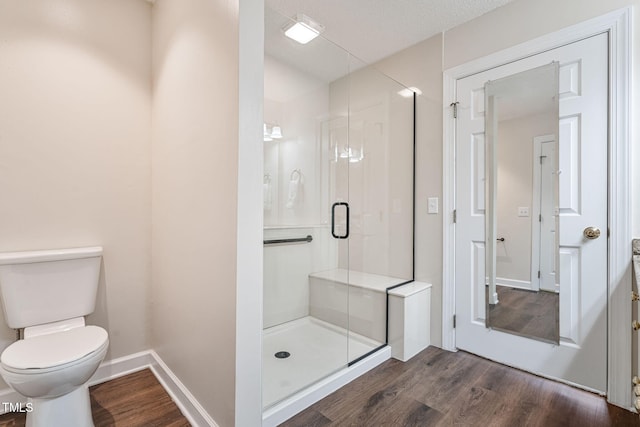 full bathroom with toilet, wood finished floors, a stall shower, and baseboards