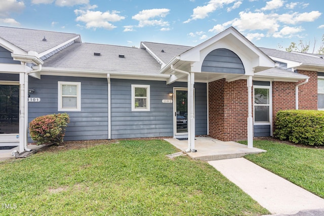 view of front of property featuring a shingled roof and a front yard