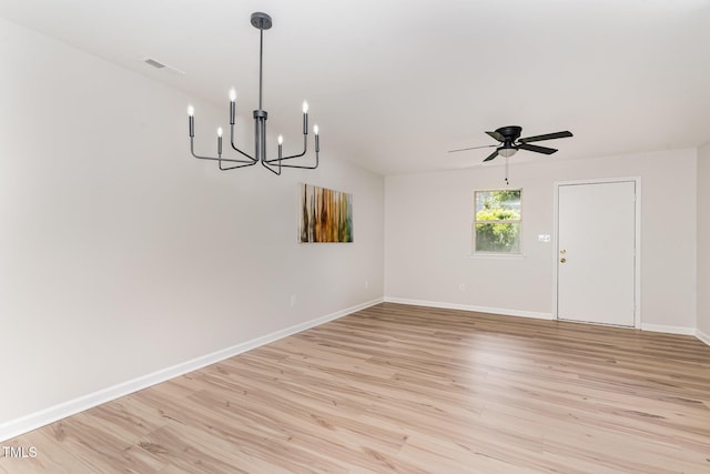 interior space with baseboards, ceiling fan with notable chandelier, light wood finished floors, and visible vents