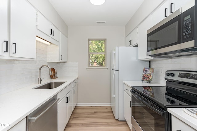 kitchen with a sink, stainless steel appliances, light wood-type flooring, backsplash, and visible vents