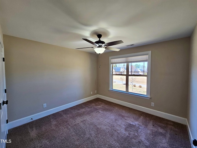 unfurnished room featuring visible vents, dark carpet, a ceiling fan, and baseboards