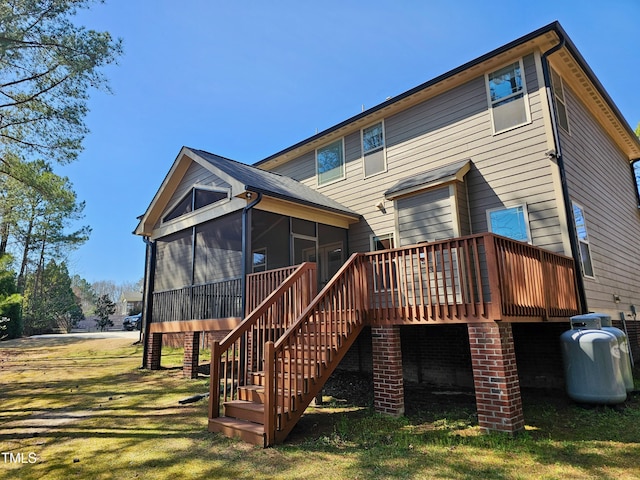 back of property with a yard, a wooden deck, stairs, and a sunroom