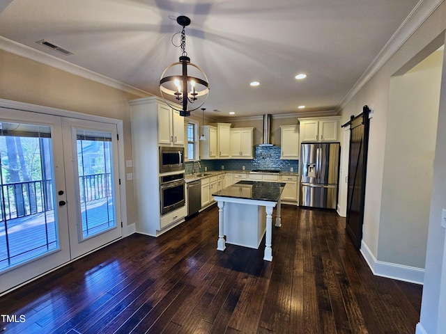 kitchen with tasteful backsplash, visible vents, a barn door, stainless steel appliances, and wall chimney exhaust hood