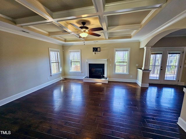 unfurnished living room with plenty of natural light, a fireplace with raised hearth, and wood finished floors