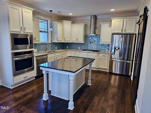 kitchen featuring dark wood-style flooring, a sink, stainless steel appliances, a barn door, and wall chimney range hood