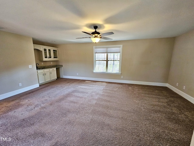 unfurnished living room with a ceiling fan, baseboards, and carpet floors