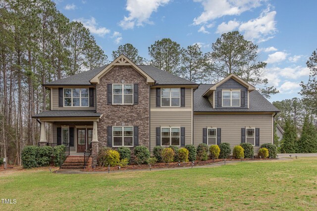 craftsman house with stone siding, a front yard, and a shingled roof