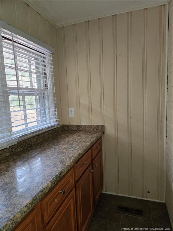 kitchen featuring dark tile patterned floors, visible vents, and brown cabinets