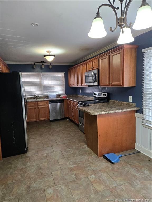 kitchen featuring brown cabinetry, a sink, hanging light fixtures, appliances with stainless steel finishes, and stone finish flooring