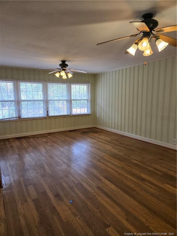 spare room featuring dark wood finished floors, ceiling fan, and baseboards