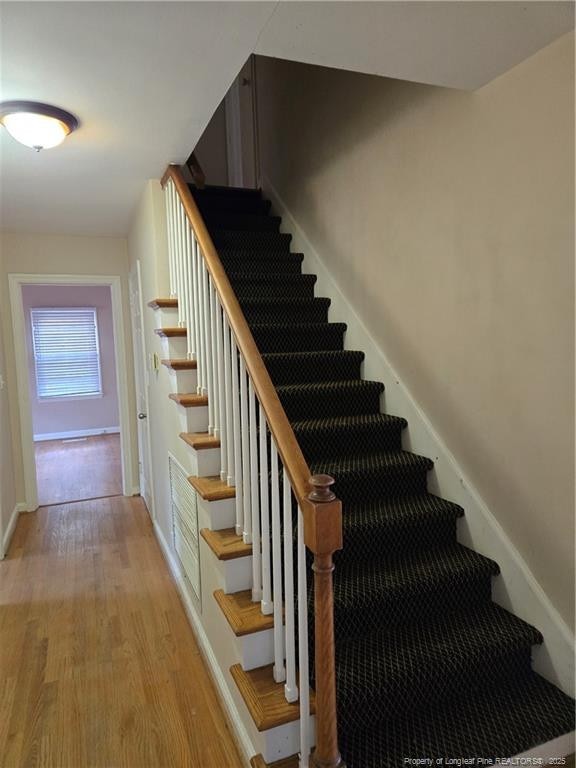 staircase featuring baseboards and wood finished floors