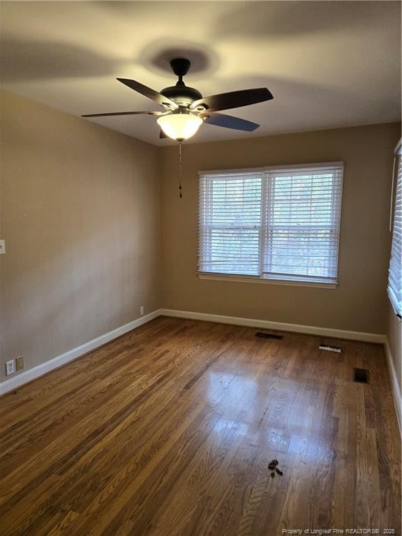 unfurnished room featuring visible vents, wood finished floors, and baseboards