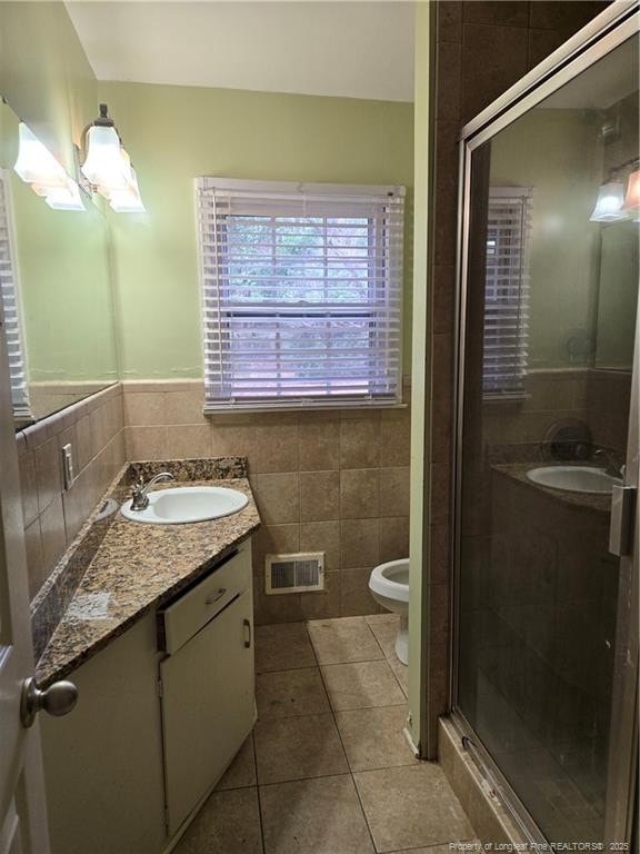 bathroom with tile patterned flooring, visible vents, tile walls, and vanity