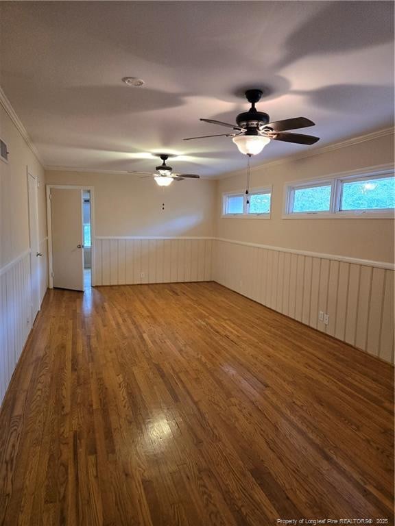 unfurnished room with visible vents, wood finished floors, wainscoting, and ornamental molding