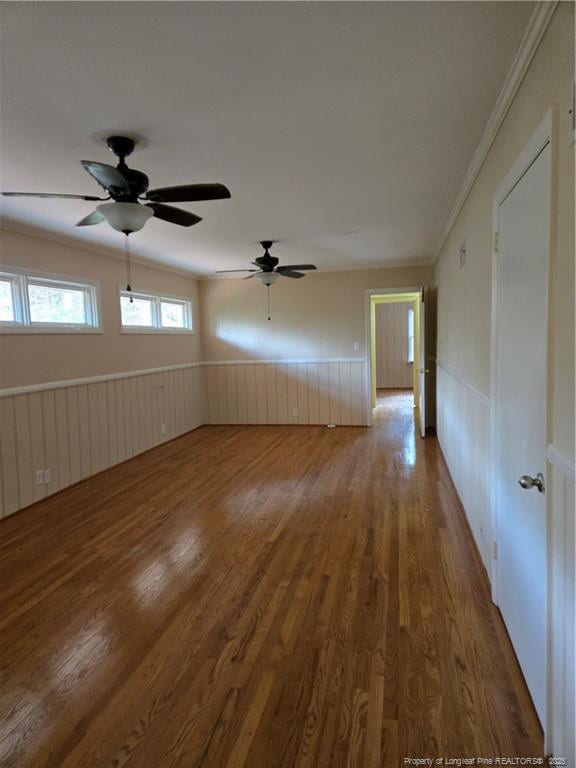 spare room featuring wood finished floors, wainscoting, and ornamental molding