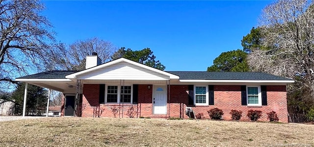 ranch-style house with brick siding, a front yard, a chimney, a carport, and driveway