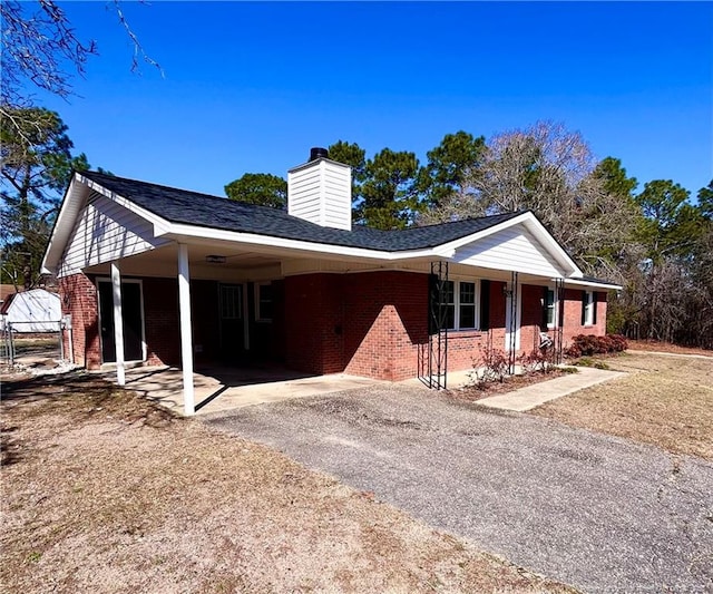 ranch-style house with brick siding, driveway, and a carport