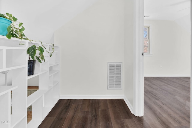 interior space featuring vaulted ceiling, visible vents, baseboards, and wood finished floors