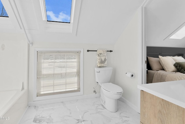 bathroom with baseboards, toilet, marble finish floor, and lofted ceiling with skylight