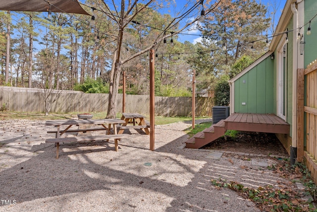 view of yard with a wooden deck, central AC unit, a fenced backyard, and a patio area