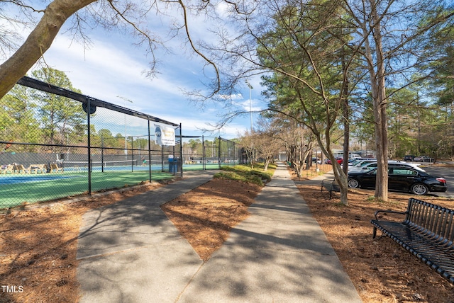 view of community with a tennis court and fence