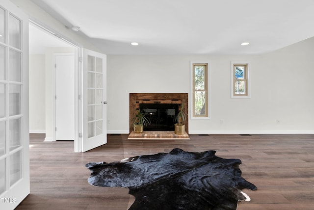 living room featuring wood finished floors, a brick fireplace, french doors, and baseboards