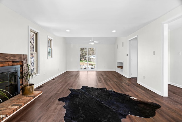 living area featuring visible vents, a brick fireplace, baseboards, and dark wood-style flooring